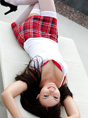 Natasha Belle posing in schoolgirl uniform and white stockings